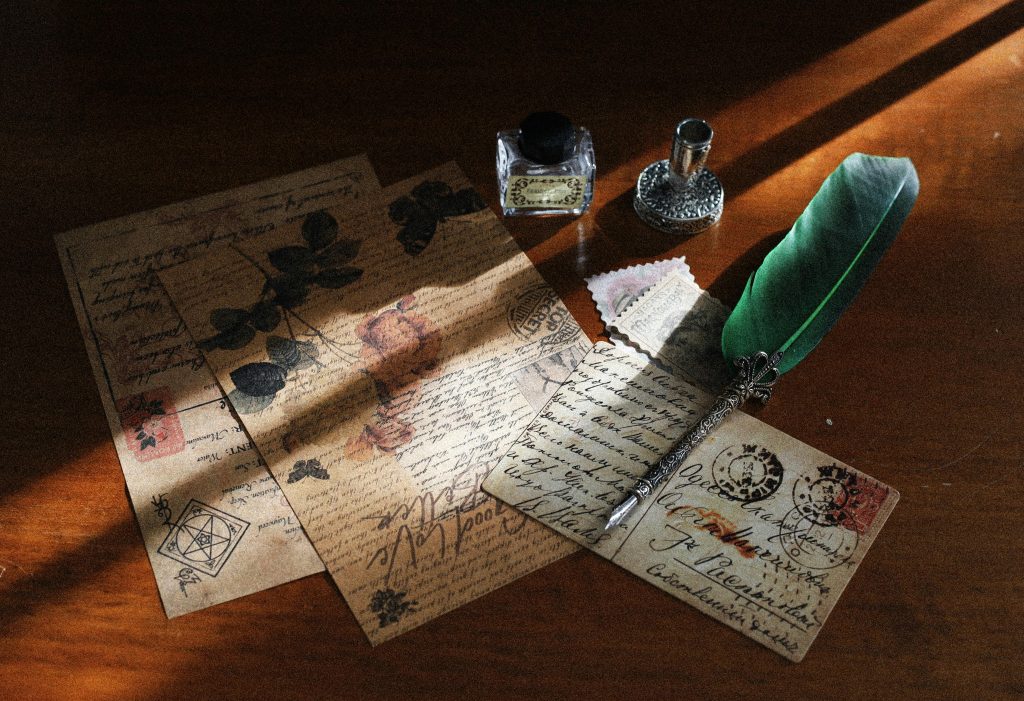 A charming still life of vintage postcards with quill and ink bottle in soft light.