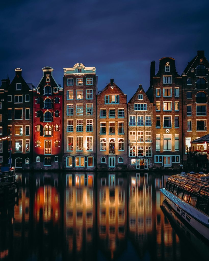 Charming canal houses along Amsterdam's waterfront, beautifully lit at dusk.