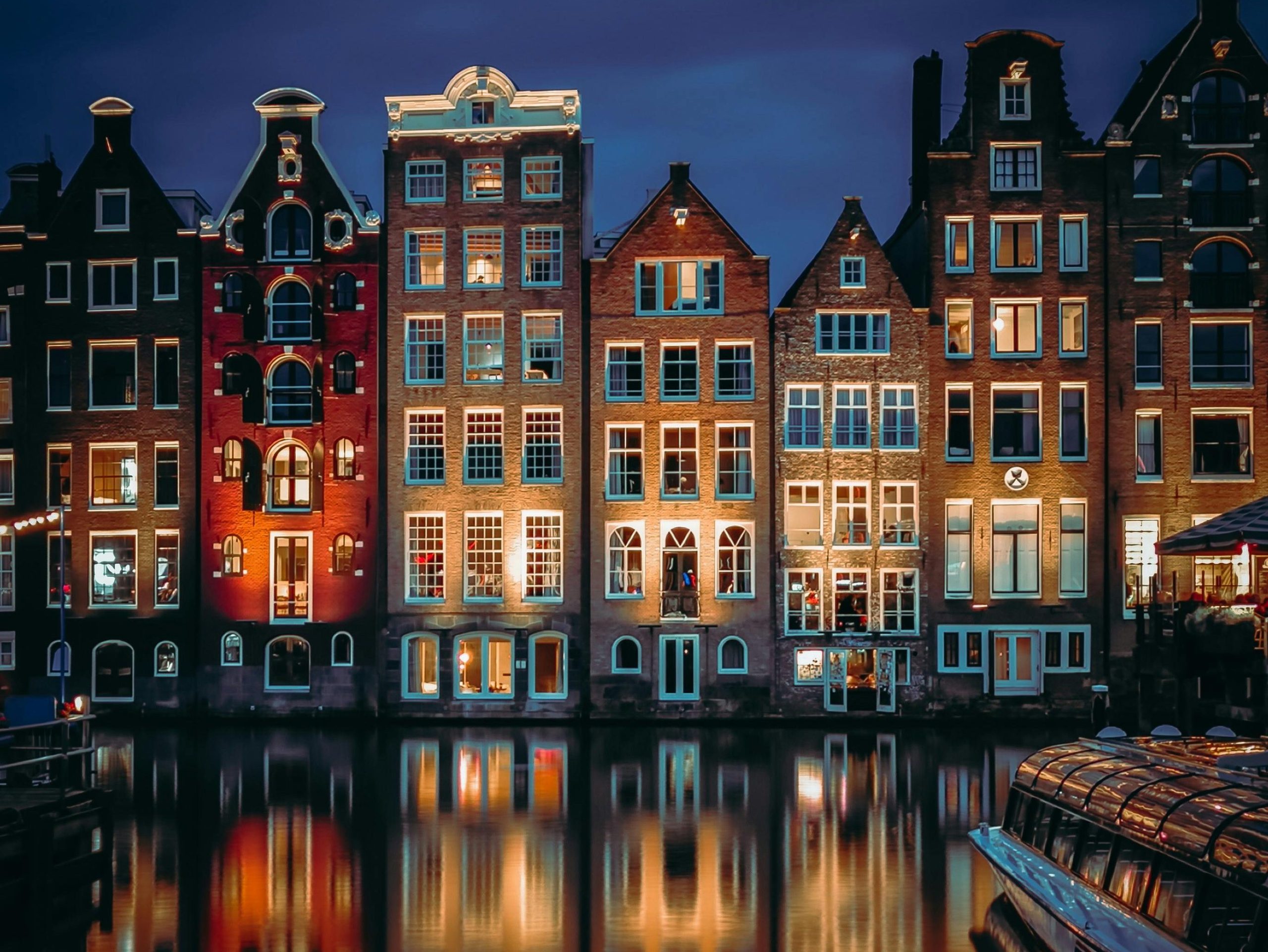 Charming canal houses along Amsterdam's waterfront, beautifully lit at dusk.