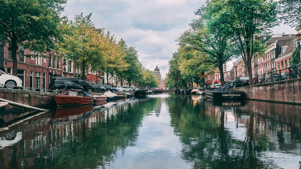 Scenic view of iconic Amsterdam canal with boats and historic buildings lining the waterway.