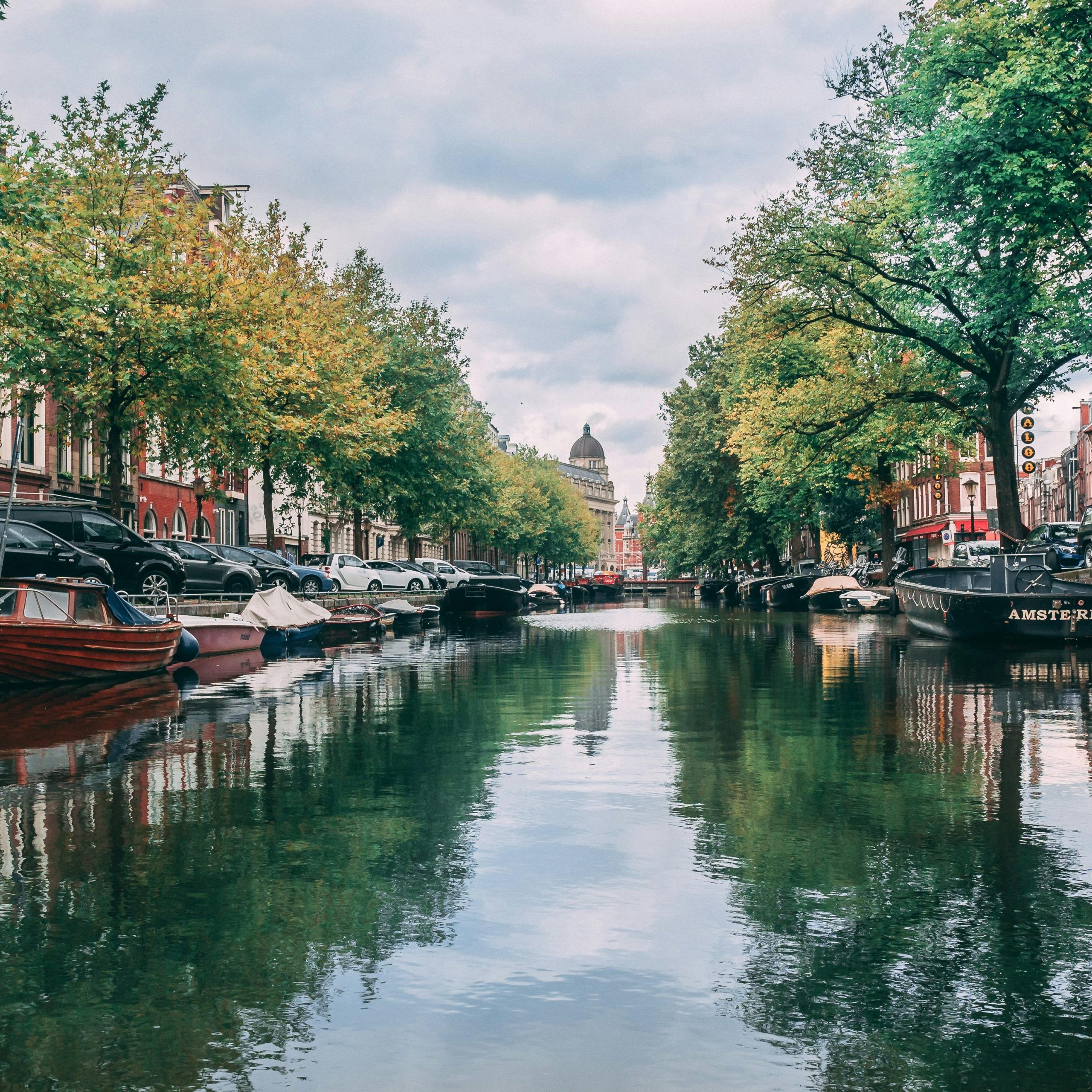 Scenic view of iconic Amsterdam canal with boats and historic buildings lining the waterway.