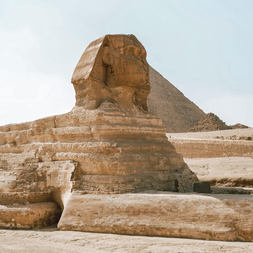 Iconic view of the Great Sphinx and Pyramid in Giza, Egypt, under a clear sky.