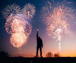 A person celebrates under vibrant fireworks in the evening sky in Kragujevac, Serbia.